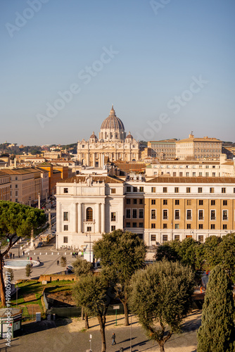 A sweeping view over Vatican City and St. Peters Basilica from Castel Sant Angelo, capturing the layout of Via della Conciliazione flanked by historic buildings and Roman pines photo