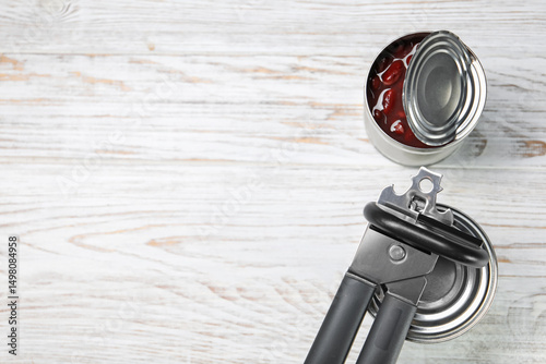 Quadro su tela Can opener and tins on white wooden table, flat lay