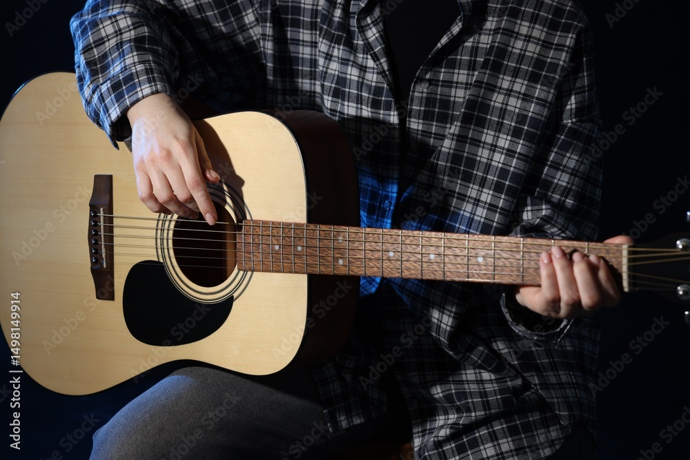 Fototapeta premium Woman playing guitar on black background, closeup