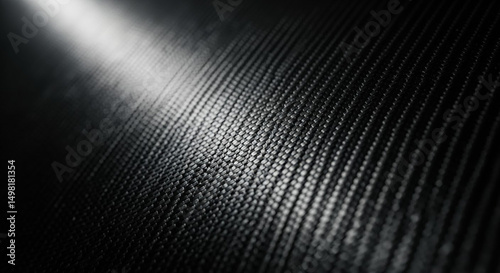 Close up view of dark carbon fiber texture with reflective light highlight