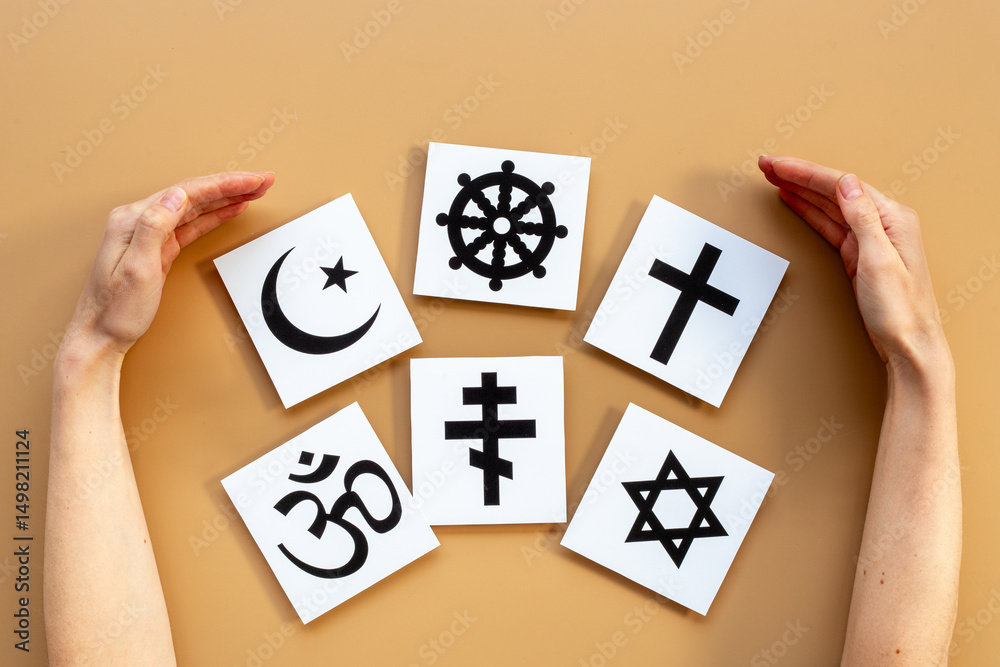 © 9dreamstudio - World religious concept. Hands holding Christianity cross, Islam crescent, Buddhism dharma wheel, Hinduism aum, Judaism David star symbols, top view