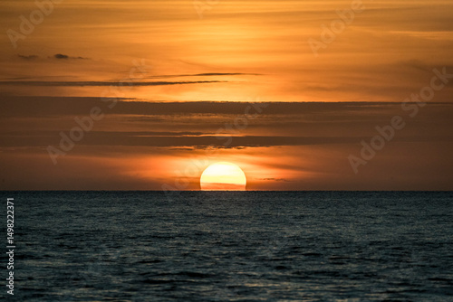 Sun sets amid light clouds in the Gulf of Mexico. photo