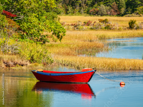 USA, Massachusetts, Cape Cod, West Harwich. Calm water surrounds a red dory moored on the Herring River
