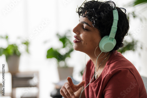 A woman with headphones is enjoying music. She's relaxing and letting the sound wash over her, maybe to de-stress or simply enjoy her favorite tunes.
