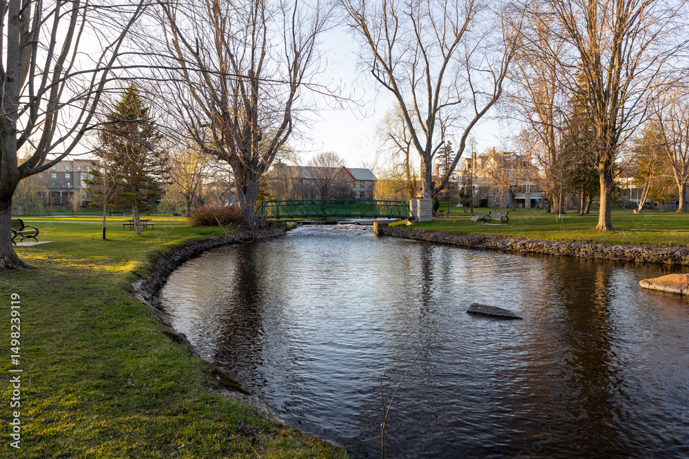 Fototapeta premium A small footbridge over a creek in spring. Stewart Park In Perth, Ontario, Canada