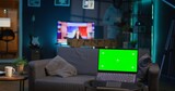 African american person enjoying music on headset next to copy space screen, feeling happy with remote work and relaxing on the sofa. Relaxed chill guy sitting in his trendy apartment. Camera B.
