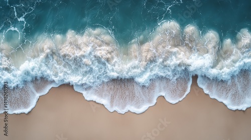 Aerial view of gentle ocean waves rolling onto a sandy beach, creating foamy patterns along the shoreline