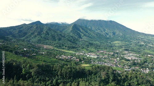 4K Drone View of Dense Town Beside Expansive Green Mountains

