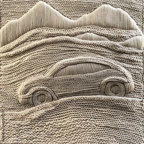 A knitted car is shown on a piece of fabric