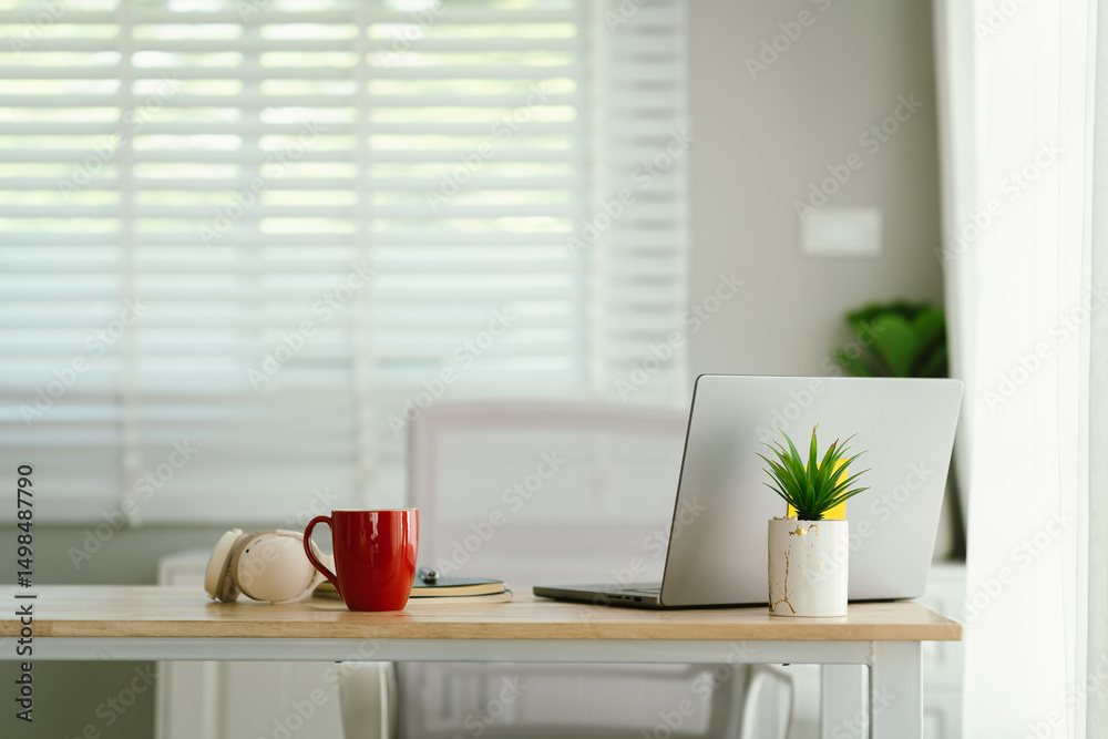 Obraz premium A modern, minimalist desk workspace with a laptop, headphones, notepad, cup of coffee, and houseplant, ready for productive remote work.