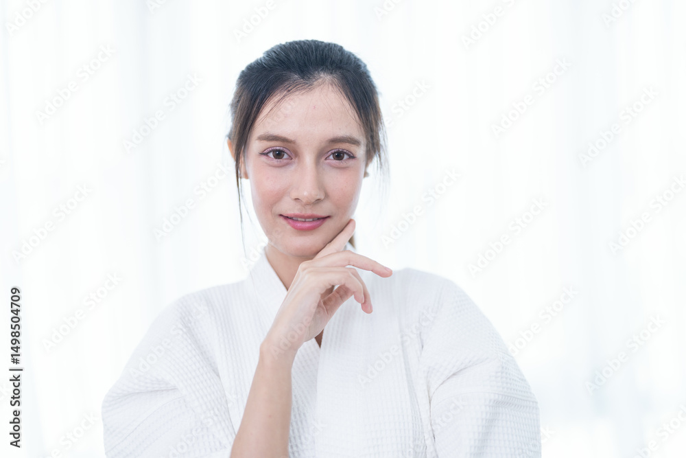 Portrait of a young Asian woman in a white bathrobe posing confidently with soft natural lighting. Portrait of a young Asian woman in a white bathrobe posing confidently with soft natural lighting.
