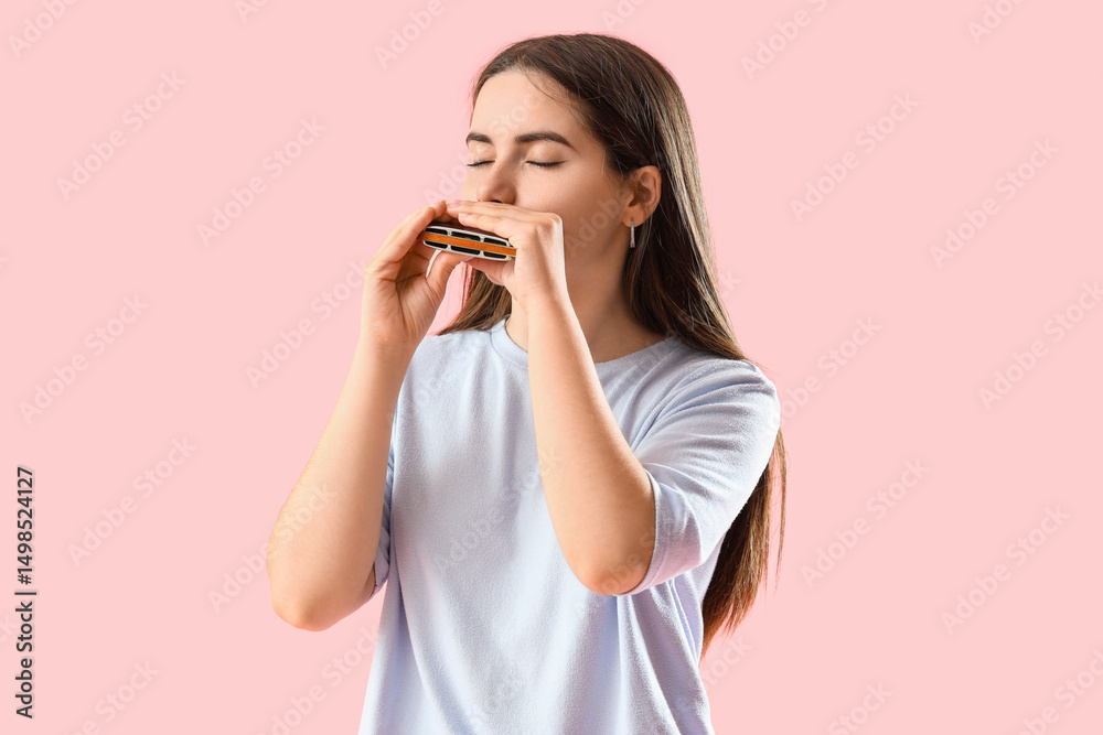 Young woman playing harmonica on pink background Young woman playing harmonica on pink background