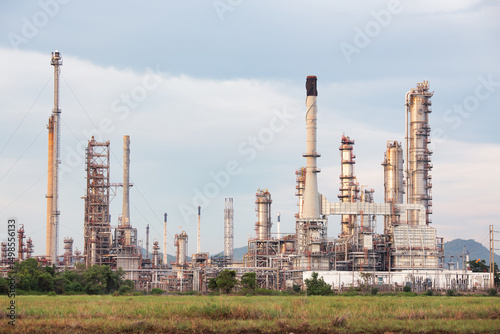 Towering oil refinery complex stands proudly beneath cloudy sky, its intricate network of steel pipes, symbolizing strength of industry, energy production and technological progress.