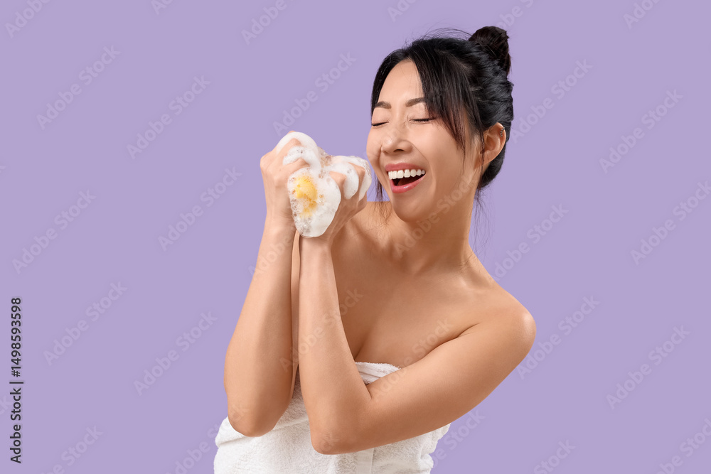 Happy young Asian woman with loofah and foam on lilac background Happy young Asian woman with loofah and foam on lilac background
