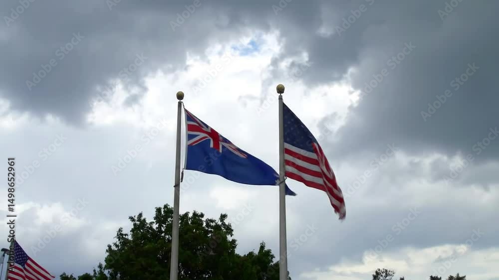 The flags of New Zealand and The United States of America flying together on a cloudy day The flags of New Zealand and The United States of America flying together on a cloudy day