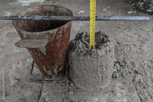Concrete slump test on construction site showing a slump cone, fresh concrete, and measuring tape for checking workability and consistency of the mix.