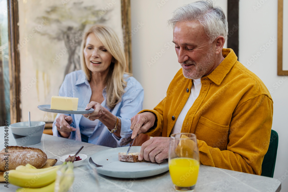 Senior couple enjoying breakfast together at home with butter and toast