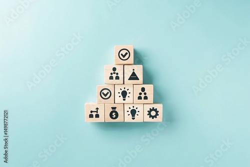 A pyramid structure made of wooden blocks, each containing different icons. The top block has a checkmark, while the lower blocks have various symbols related to processes or tasks