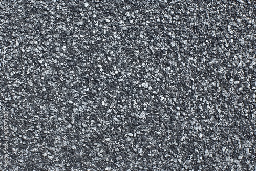 Dark gray asphalt texture with small stones. Close-up view shows the detailed surface