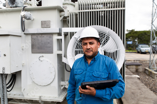 Engineer posing with electric transformer at wind farm for renewable energy inspection