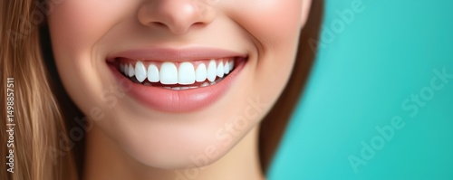 Bright and radiant smile of a young woman with perfect white teeth against turquoise background