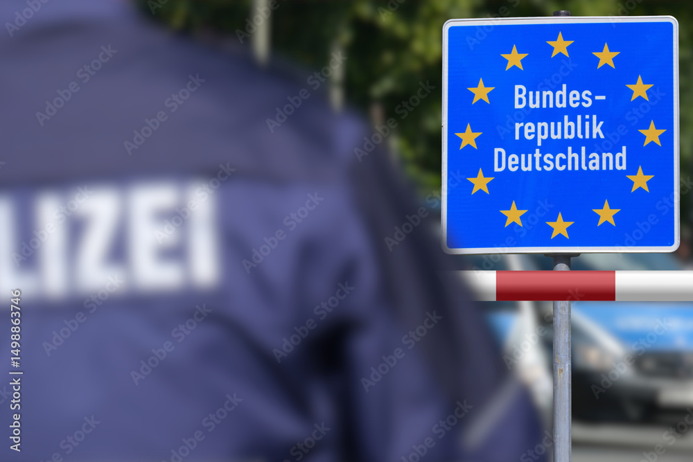 Fototapeta premium Ein Polizist steht an der deutschen Grenze vor dem Schild Bundesrepublik Deutschland