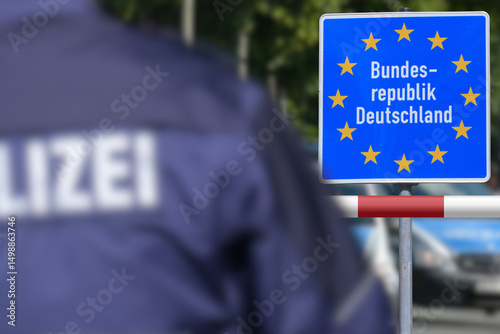 Ein Polizist steht an der deutschen Grenze vor dem Schild Bundesrepublik Deutschland