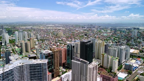 Wide aerial shot over Makati's skyline in the morning sun, showing the city’s dense buildings, business center, and the expansive horizon stretching toward the bay and distant areas.