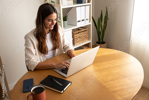 High angle view of young caucasian woman working at home office. Happy female entrepreneur using laptop. Copy space