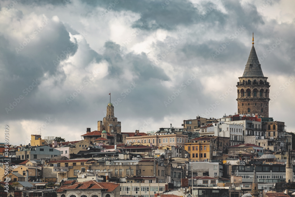 Naklejka premium Skyline of Istanbul featuring historic architecture and Galata Tower under dramatic cloudy sky