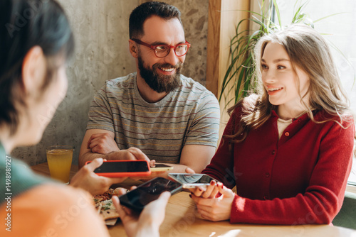 Group of smiling friends sharing content on smartphones in cafe photo