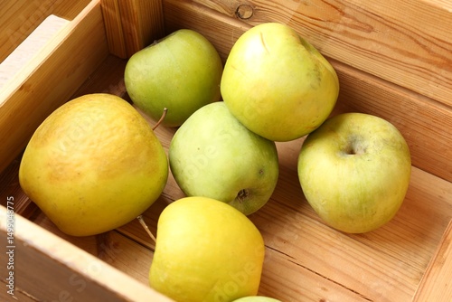 Damaged green apples in wooden crate, closeup