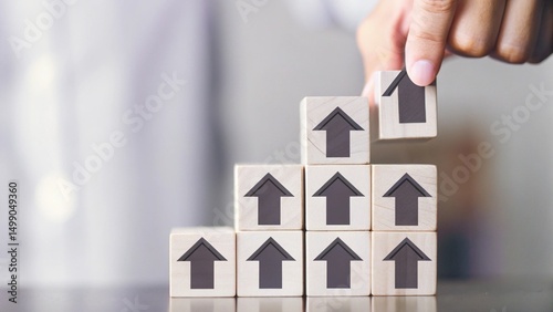A hand is placing a wooden block with a house icon on top of a stack of blocks