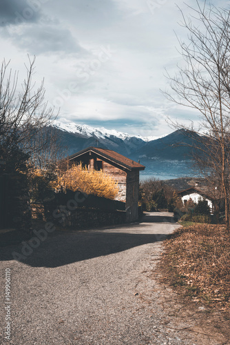 wooden house at spring time near lake como and snowy peaks background