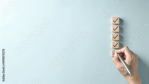 A hand holding a pen is checking off wooden boxes on a vertical list of square blocks