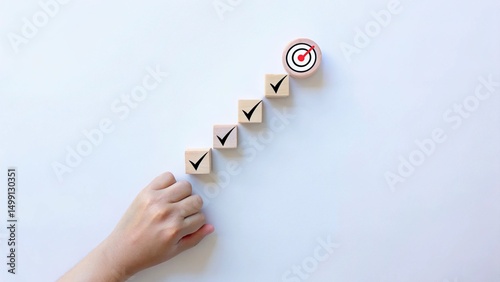 A hand places a circular block with a target icon at the end of a sequence of wooden blocks with checkmarks