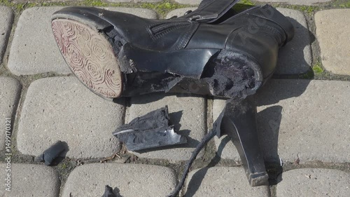 sole flew off with heel in women's boots, old torn women's boots lie on cobblestones