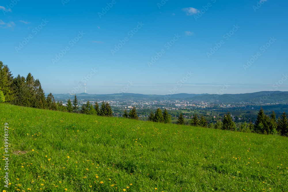 Obraz premium View of the city of Liberec from nearby hills around Jested mountain. Urban landscape surrounded by greenery and hills, typical northern Bohemia summer scenery