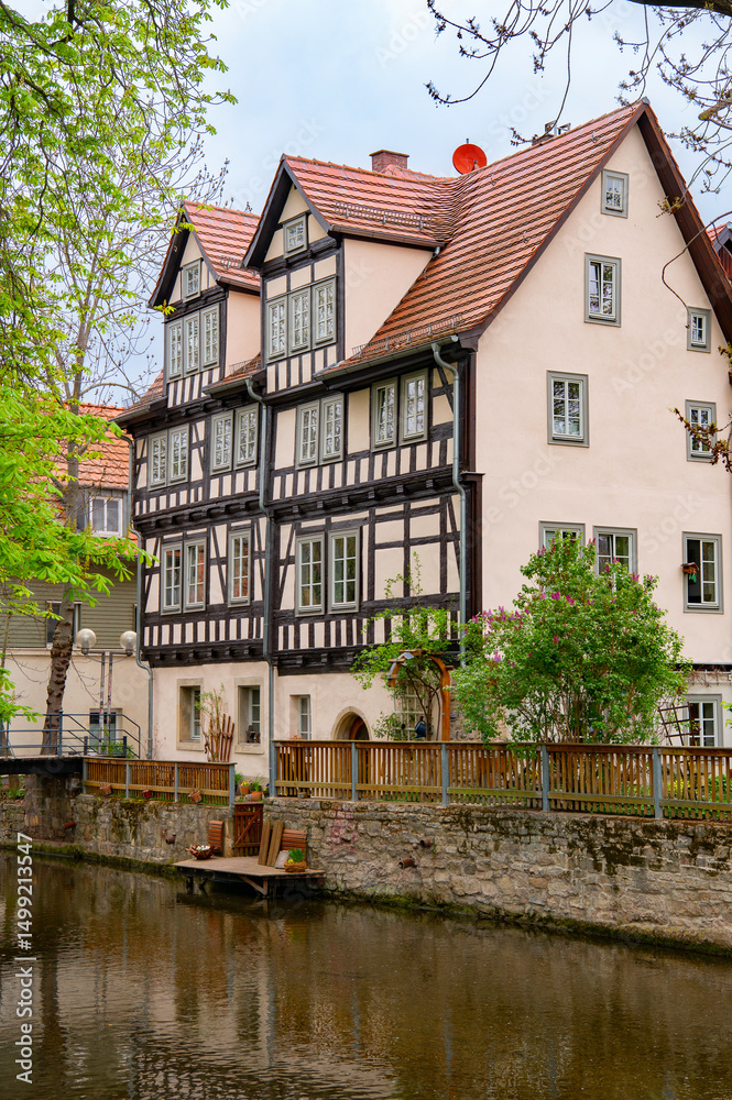 Naklejka premium Traditional half-timbered house on the Gera river in Erfurt, Thuringia, Germany. Reflection in water. Travel photography
