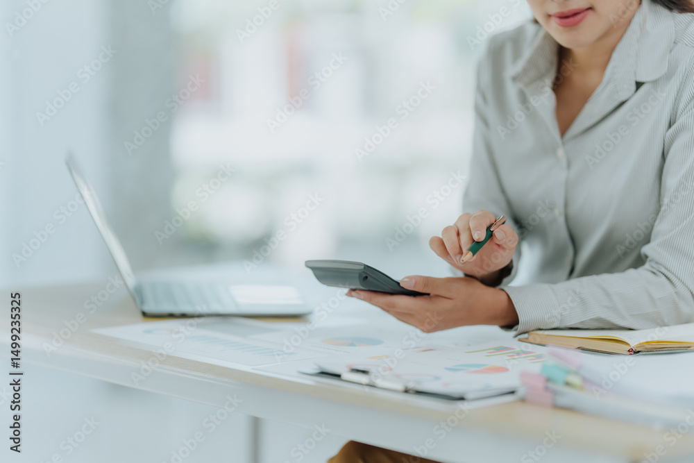 Fototapeta premium Woman Calculating Finances at Desk
