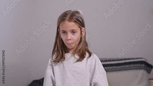 Pretty girl in casual clothes adjusting her hair and making playful face, smiling at camera while at home, enjoying the moment with cheerful expression