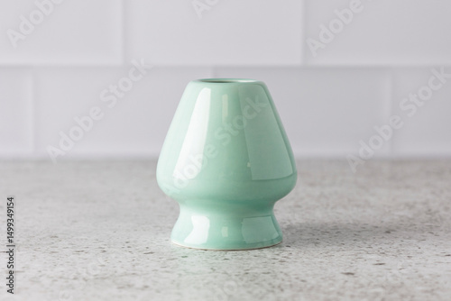 Light green ceramic matcha whisk holder standing on kitchen countertop