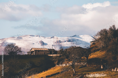 mountain landscape of lessinia in the morning, with snowy mountains in tha background and a stone hut