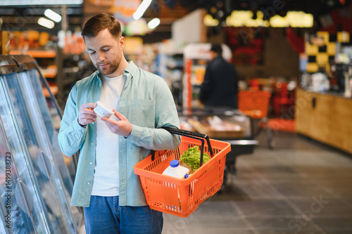 Customer choosing groceries in supermarket reading product label