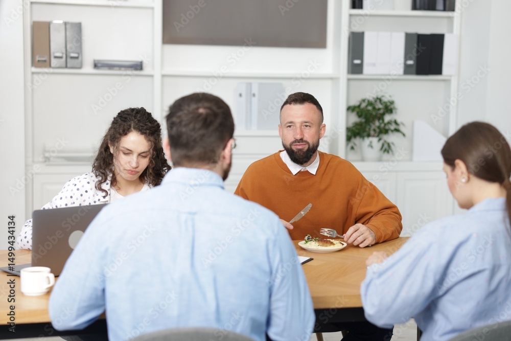 Fototapeta premium Colleagues eating and chatting during lunch break in office