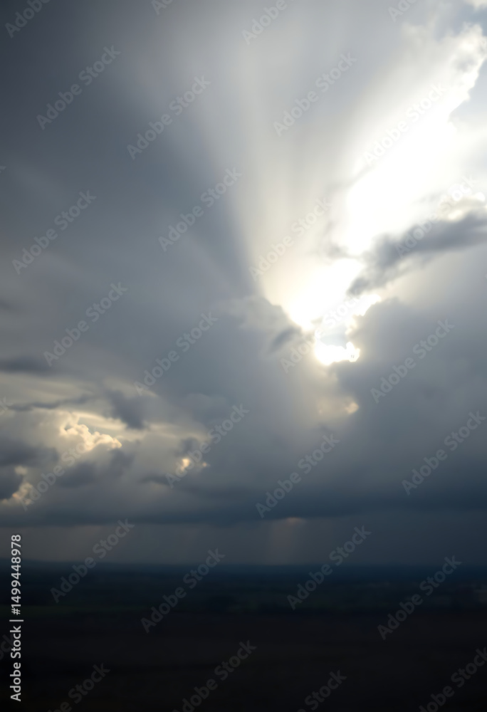 Naklejka premium sun is shining through the clouds in the sky