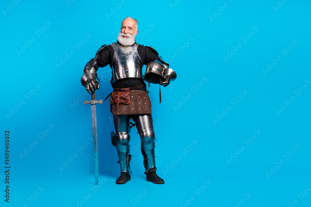 Naklejka premium Elderly Man Dressed as a Medieval Knight Holding Sword Against Blue Background