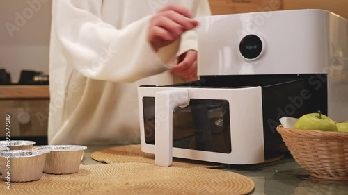Woman preparing muffins in a modern air fryer
