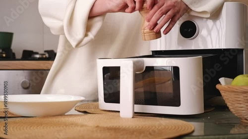 Woman preparing and cooking corn on the cob in an air fryer in a domestic kitchen