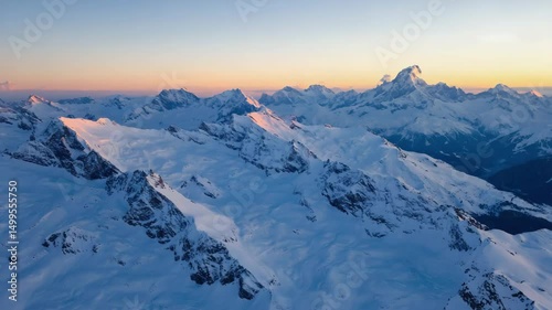 Aerial View of Snow-Covered Mountain Range at Sunrise with Golden Horizon
